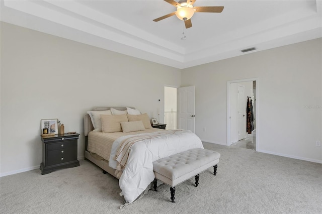 carpeted bedroom with a raised ceiling and ceiling fan