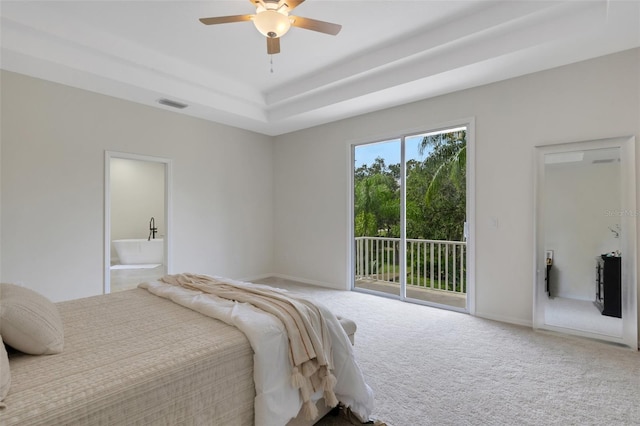 bedroom featuring carpet, a tray ceiling, access to outside, ensuite bath, and ceiling fan