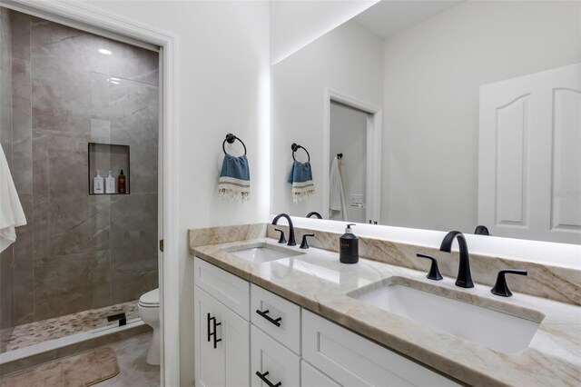 bathroom with toilet, a tile shower, and vanity