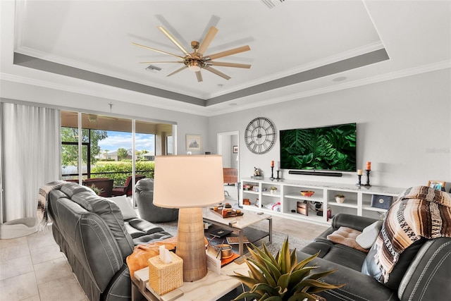 tiled living room with ornamental molding, a raised ceiling, and ceiling fan