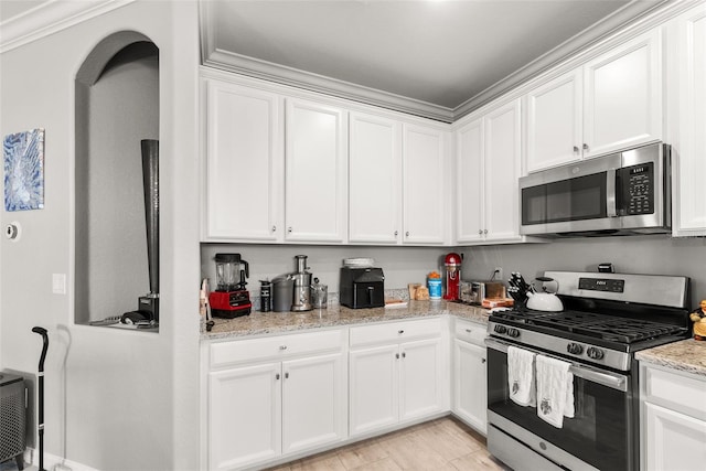 kitchen with ornamental molding, light stone counters, stainless steel appliances, and white cabinets