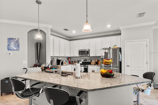 kitchen featuring decorative light fixtures, a kitchen bar, stainless steel appliances, and a kitchen island with sink