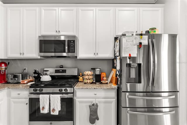 kitchen with white cabinets, light stone counters, and stainless steel appliances