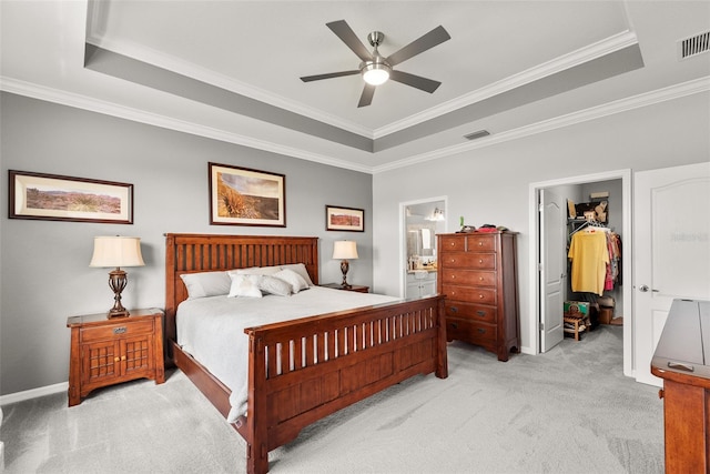 carpeted bedroom featuring connected bathroom, a walk in closet, ceiling fan, and a tray ceiling