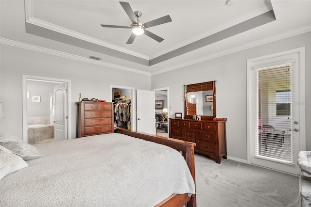 bedroom with a tray ceiling, ceiling fan, a walk in closet, and ornamental molding