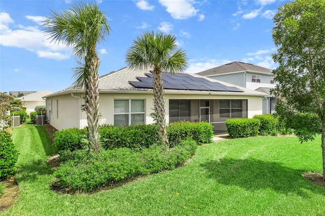 back of property with a yard, central AC unit, solar panels, and a sunroom