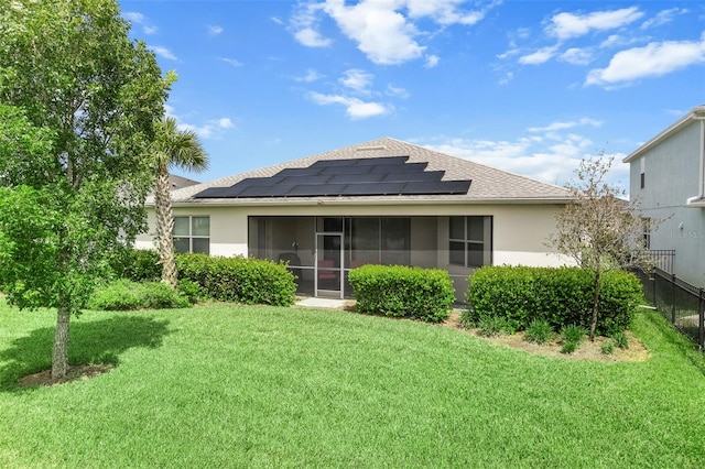 rear view of property with a lawn, solar panels, and a sunroom