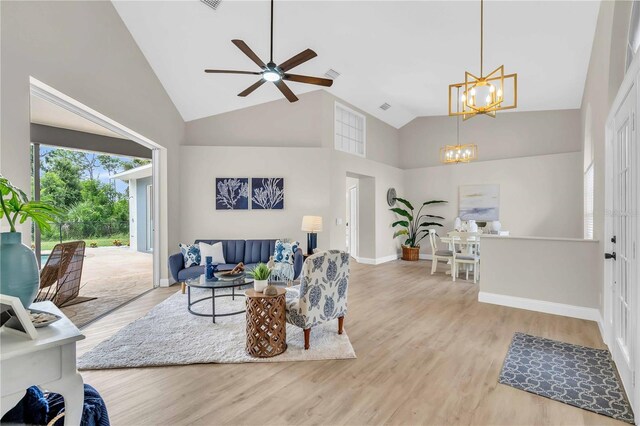 living room with ceiling fan with notable chandelier, high vaulted ceiling, and light hardwood / wood-style floors