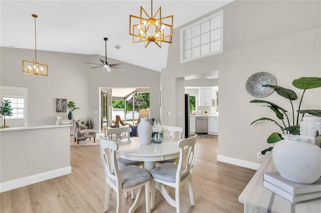 dining area featuring ceiling fan with notable chandelier, high vaulted ceiling, plenty of natural light, and light hardwood / wood-style flooring