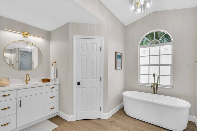 bathroom featuring vanity, a bath, hardwood / wood-style floors, and lofted ceiling