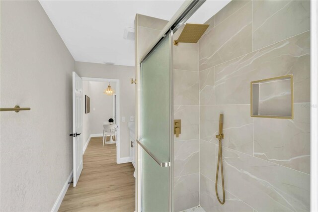 bathroom with wood-type flooring and a shower with shower door