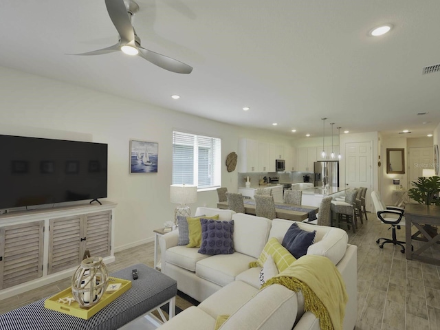 living room with ceiling fan with notable chandelier and light hardwood / wood-style floors