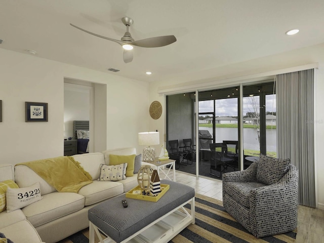 living room with a water view, ceiling fan, and hardwood / wood-style flooring