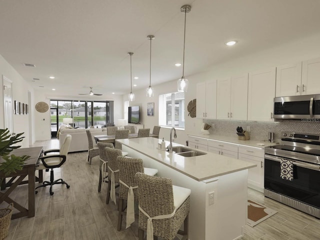 kitchen featuring decorative light fixtures, sink, ceiling fan, appliances with stainless steel finishes, and white cabinets