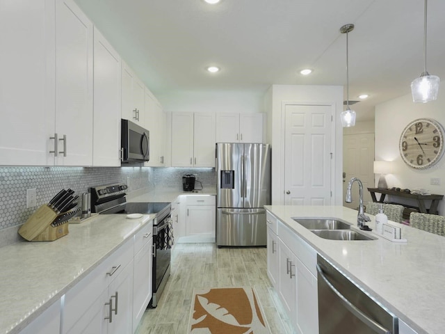 kitchen with appliances with stainless steel finishes, light hardwood / wood-style floors, white cabinetry, and sink