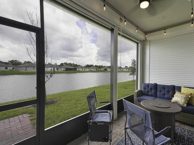 sunroom with a water view and ceiling fan