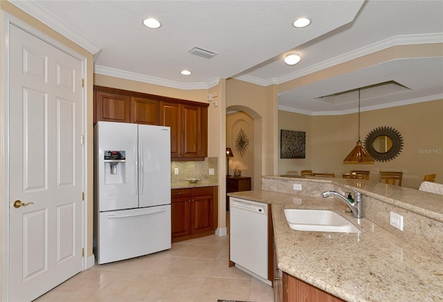 kitchen with white appliances, light tile patterned floors, decorative light fixtures, light stone counters, and sink