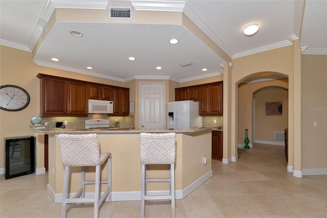 kitchen featuring light tile patterned floors, white appliances, a breakfast bar area, and a center island