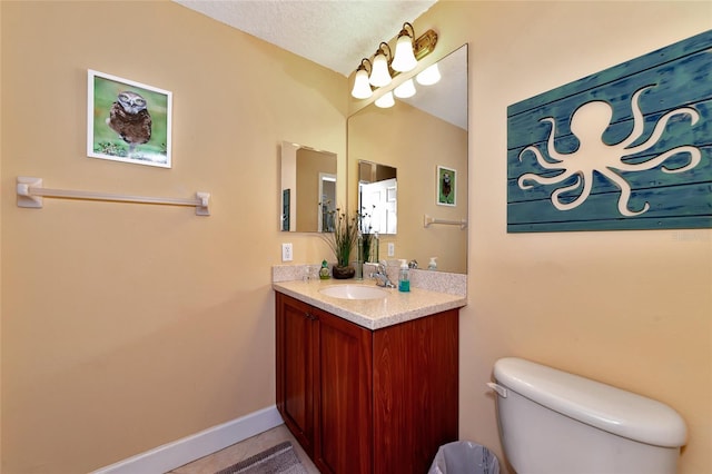 bathroom with vanity, toilet, and a textured ceiling