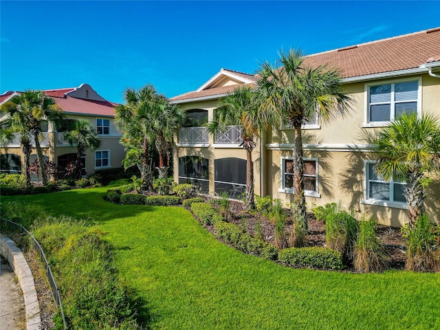 rear view of house featuring a balcony and a lawn