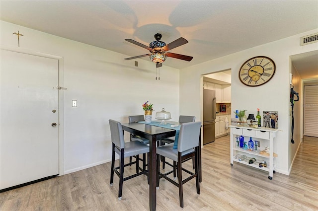 dining space with a textured ceiling, light hardwood / wood-style floors, and ceiling fan