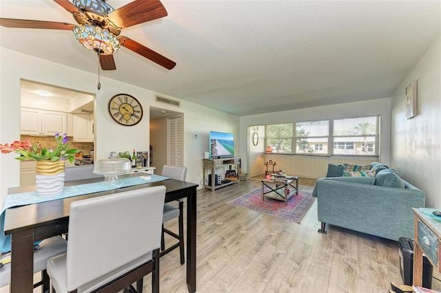 dining area featuring ceiling fan, a textured ceiling, and light wood-type flooring