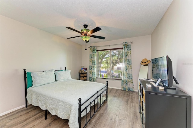 bedroom with ceiling fan, light hardwood / wood-style floors, and a textured ceiling