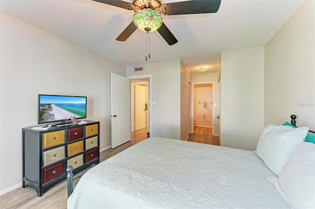 bedroom featuring ceiling fan, connected bathroom, and light hardwood / wood-style flooring