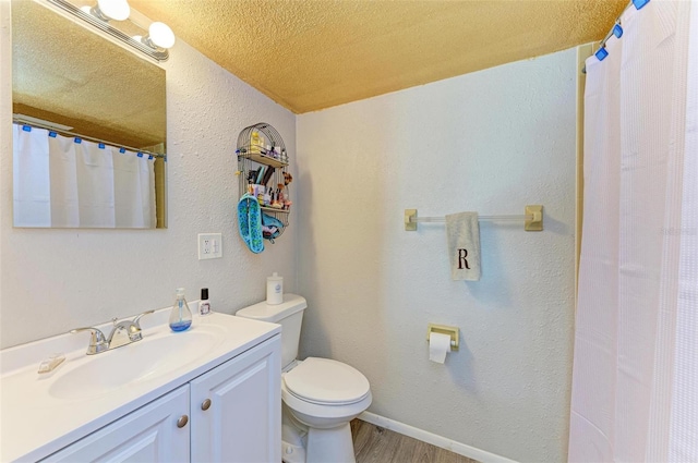 bathroom with wood-type flooring, vanity, a textured ceiling, and toilet