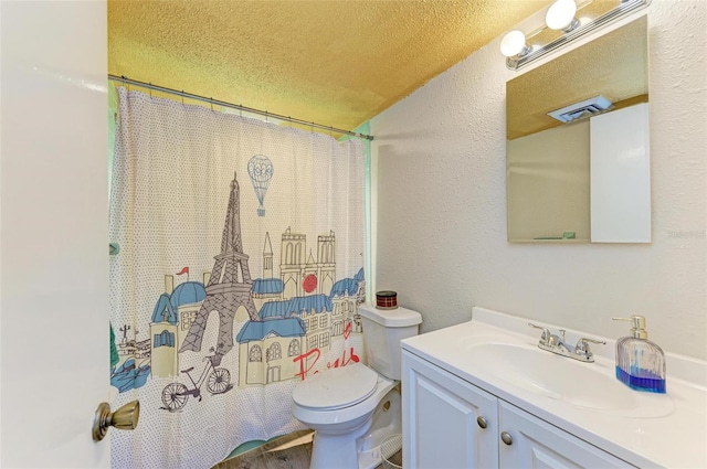 bathroom featuring vanity, a textured ceiling, and toilet