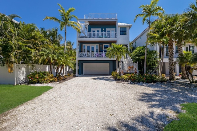 coastal inspired home featuring a balcony, a garage, and a porch