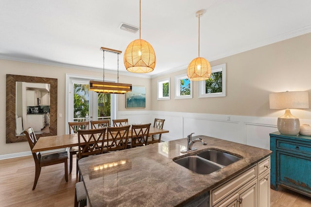 kitchen with light hardwood / wood-style flooring, pendant lighting, ornamental molding, and sink