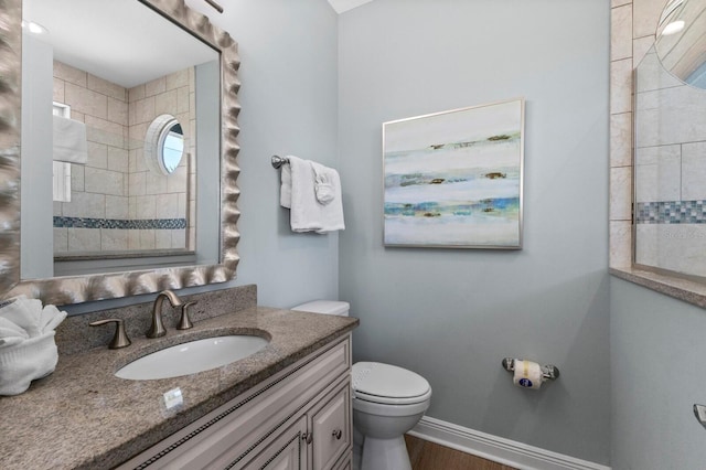 bathroom with wood-type flooring, vanity, and toilet