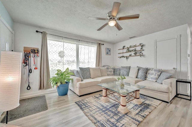 living room with visible vents, a textured ceiling, a ceiling fan, and wood finished floors