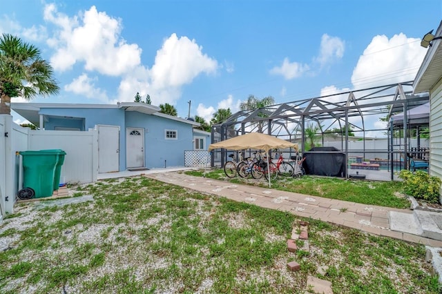 view of yard with glass enclosure and fence