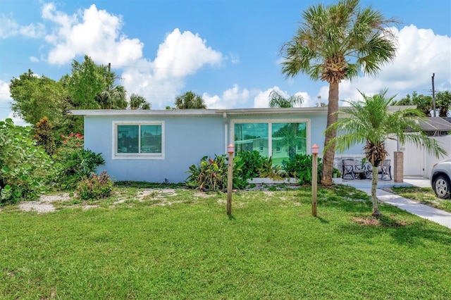 ranch-style home with a front lawn and stucco siding