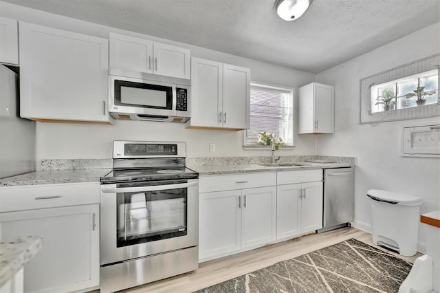 kitchen featuring appliances with stainless steel finishes, white cabinetry, a healthy amount of sunlight, and light hardwood / wood-style floors