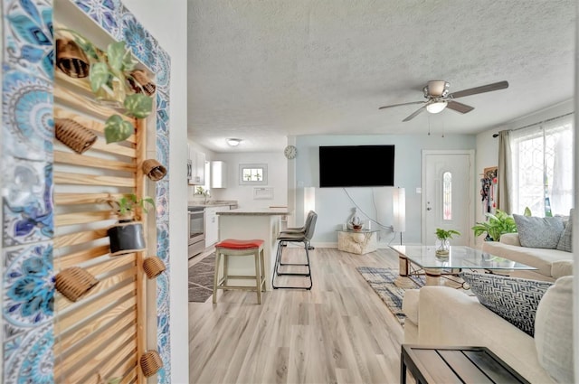 living room featuring a textured ceiling, ceiling fan, and light hardwood / wood-style floors