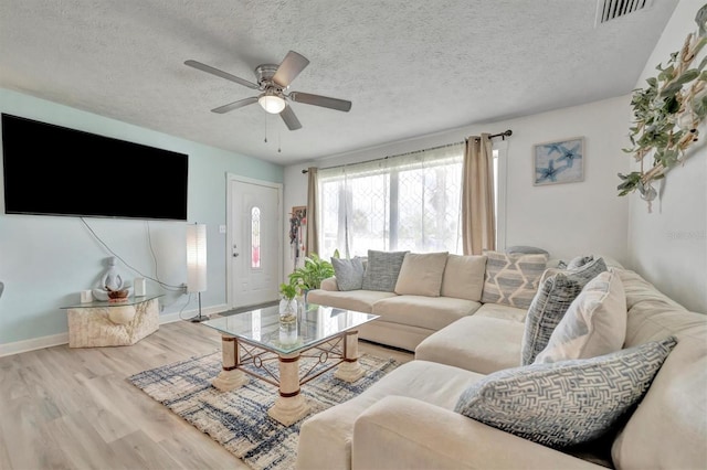 living room featuring light wood-type flooring, a textured ceiling, and ceiling fan