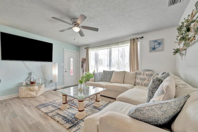 living room with visible vents, a textured ceiling, a ceiling fan, and wood finished floors
