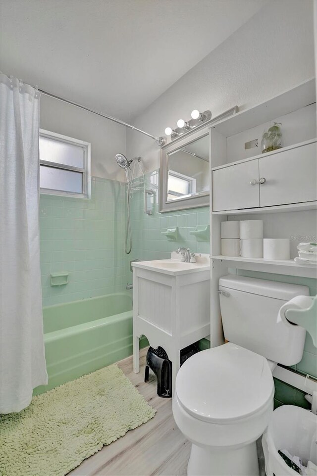 full bathroom with shower / tub combo with curtain, toilet, tile walls, and a wealth of natural light