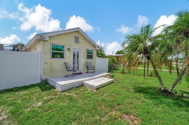 rear view of house with a deck, fence, and a lawn