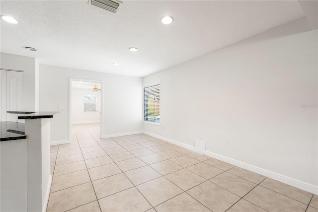 tiled spare room with a textured ceiling