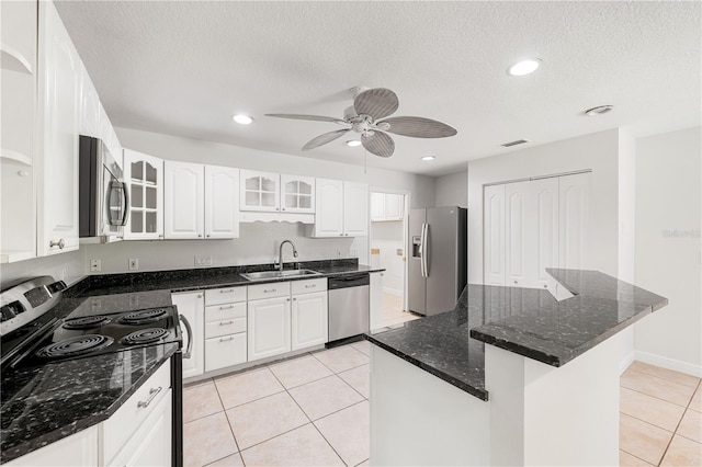 kitchen featuring dark stone countertops, light tile patterned floors, sink, ceiling fan, and appliances with stainless steel finishes