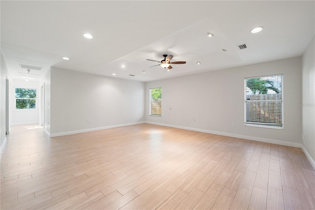 empty room with light wood-type flooring, ceiling fan, and a healthy amount of sunlight