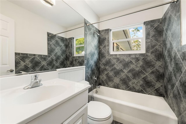 full bathroom with vanity, a healthy amount of sunlight, tiled shower / bath combo, and toilet