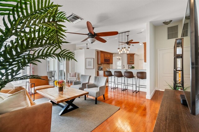 living room featuring light wood-type flooring, ceiling fan, and a towering ceiling