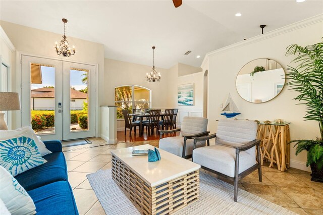 living room with a notable chandelier, ornamental molding, light tile patterned floors, vaulted ceiling, and french doors