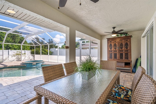 view of swimming pool with glass enclosure, a fenced backyard, and ceiling fan