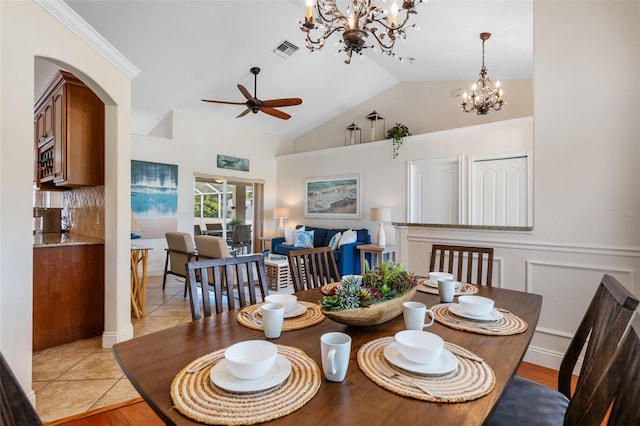 dining space featuring ceiling fan with notable chandelier, vaulted ceiling, and light wood-type flooring